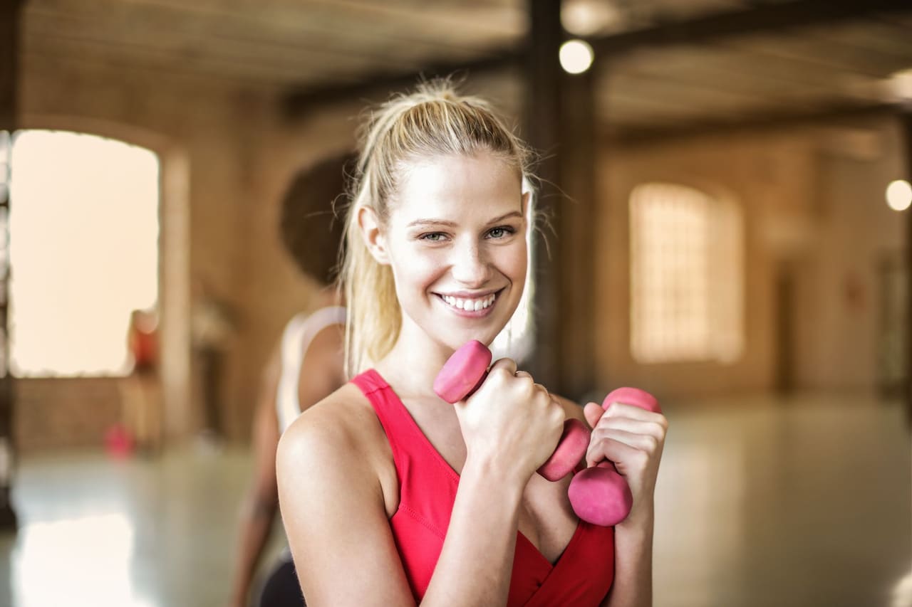 A smiling woman working out with dumbbells
