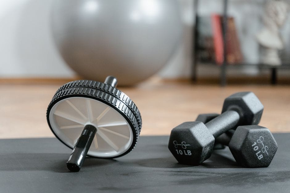 a beginner home gym with dumbbells and a mat in a small room
