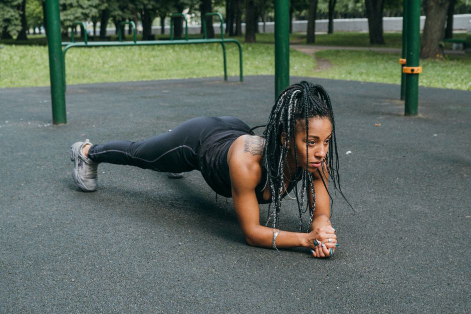 African American woman doing a plank exercise outdoors in a park, promoting fitness and healthy lifestyle.