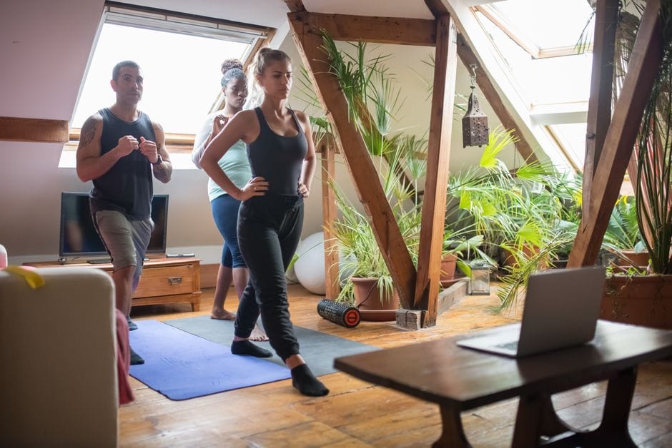 Group of adults participating in a fitness session in a cozy loft apartment with natural light.