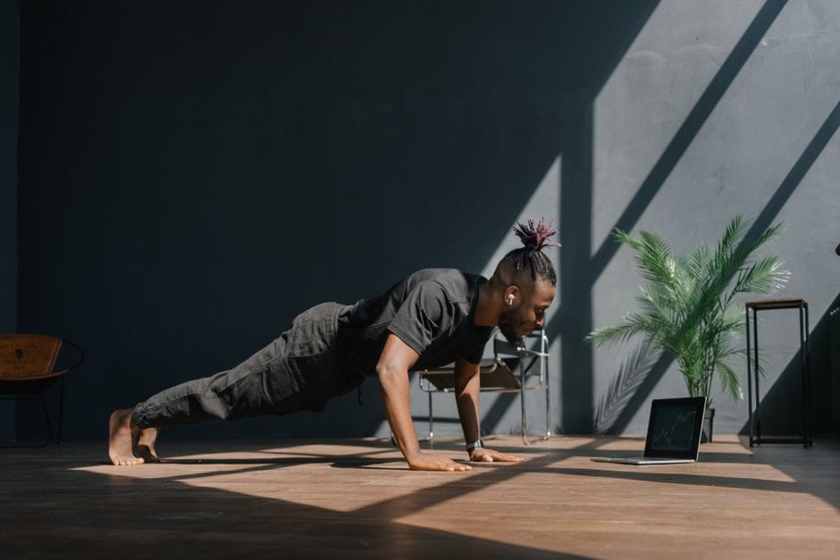 A person performing a push-up in a straight plank position on a gym floor