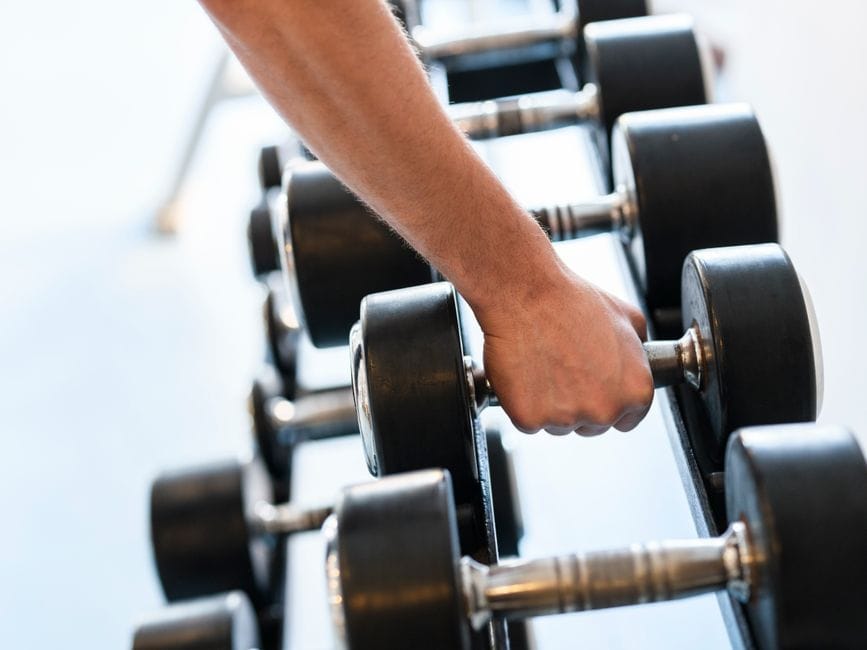 close-up of hands gripping heavy dumbbells during a farmer's carry