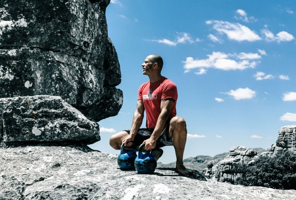 person doing a kettlebell farmer's carry outdoors