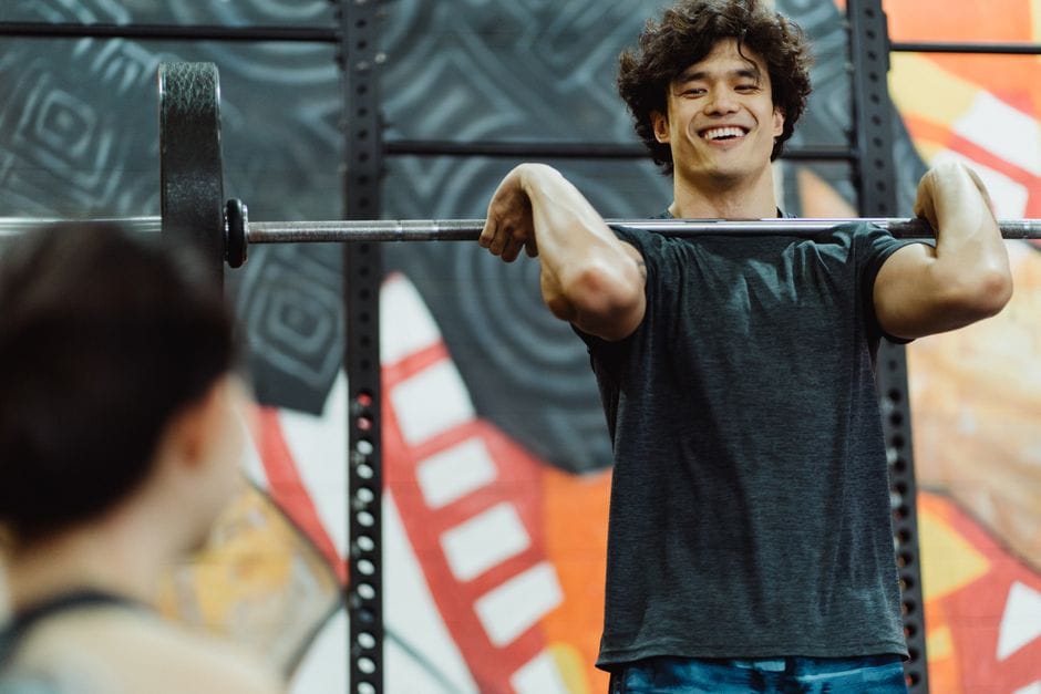 Man holding a barbell in the front rack position at the top of a front squat