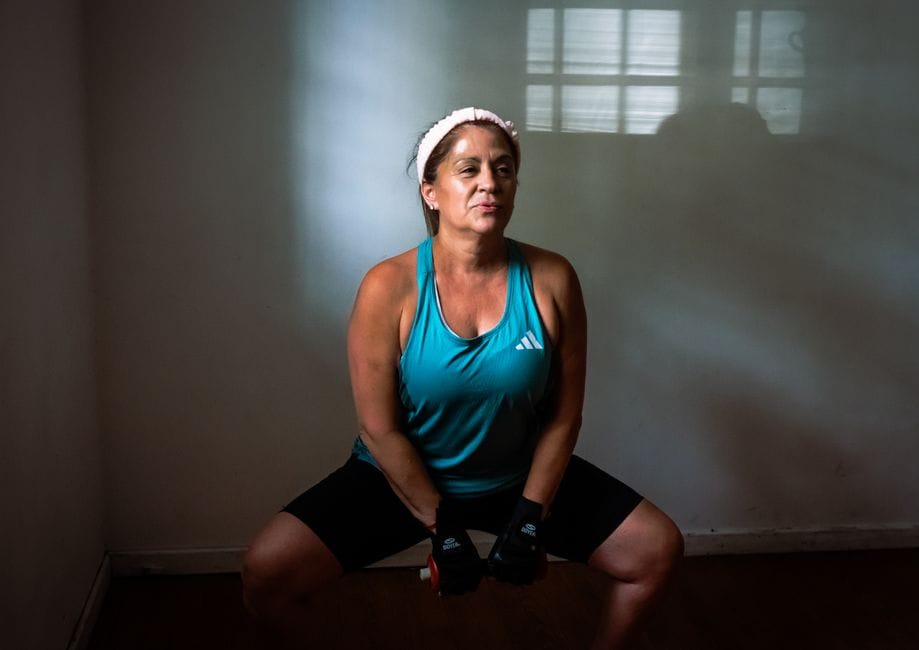 Person at the bottom of a deep goblet squat with dumbbell held at chest