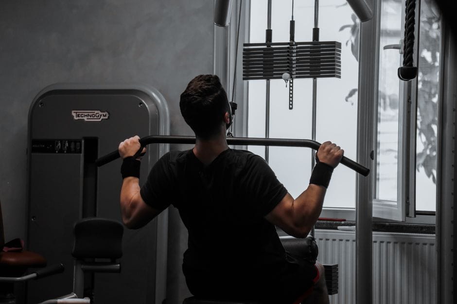 A man working out on a lat pulldown machine in a gym, focusing on strength building.