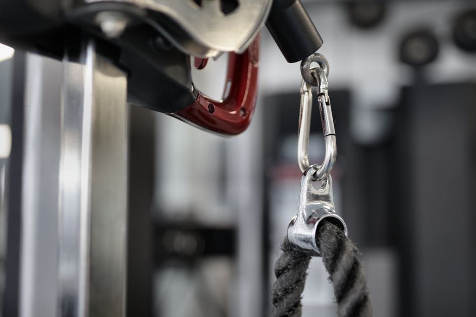 Rope, straight bar, and V-bar cable attachments lined up at a gym